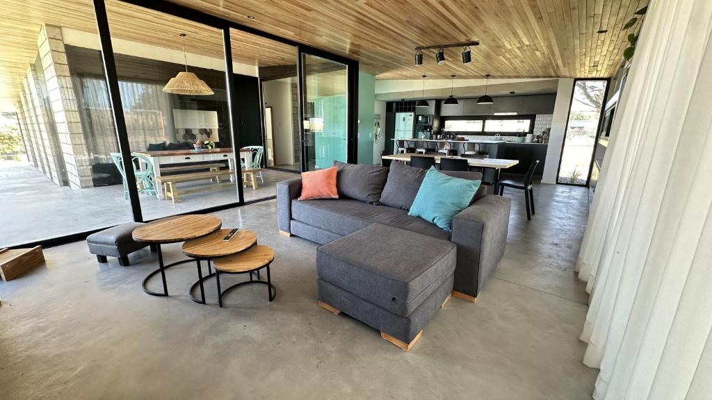 a living room with a couch and a table at Casa Pit - Casa en chapa con pileta Barrio Privado 6PX I Hola Sur in Mar del Plata