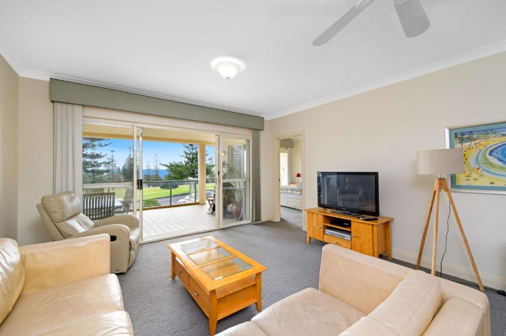 a living room with a couch and a television at Harbourwatch 11 18 Burrawan Street in Port Macquarie