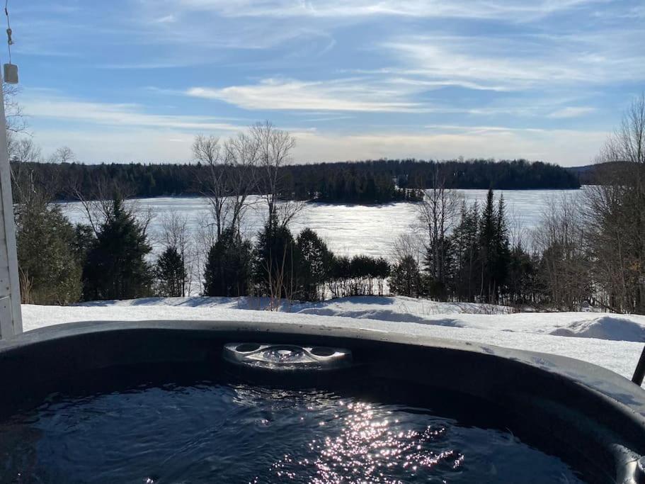 bañera con vistas a un lago cubierto de nieve en Private Waterfront SPA Perfect Sunsets Lake, en Nominingue