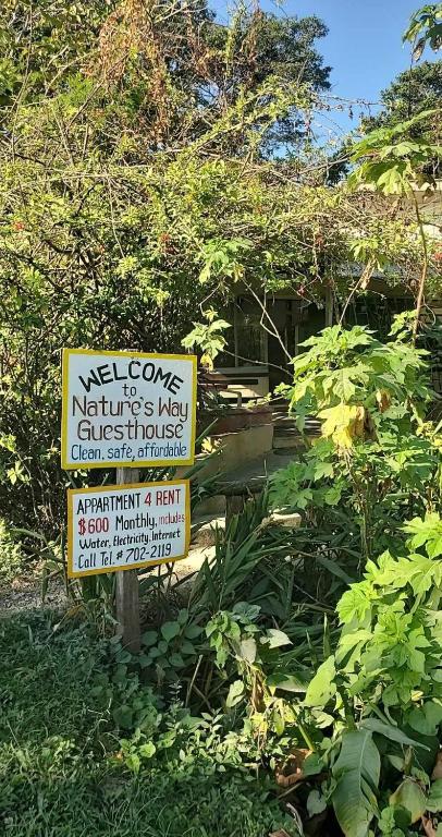 een bord voor een tuin met een huis bij Schmidt’s Natures Way Guesthouse in Punta Gorda