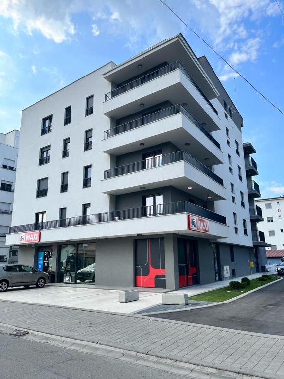 a large white building with a car parked in front of it at LadyDi apartman in Banja Koviljača
