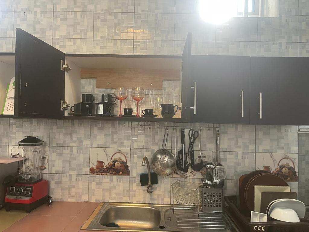 a kitchen with black cabinets and a sink with wine glasses at Charly Cabanadeluxe in Cotonou