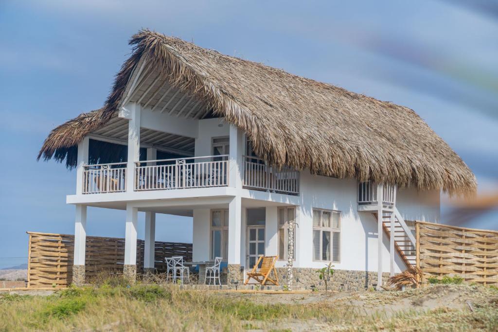 a house with a thatched roof on the beach at Casa Azul Departamentos frente al mar in Máncora