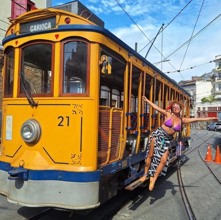 a woman sitting on the side of a yellow tram at Casa Por do Sol in Rio de Janeiro