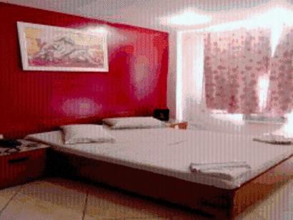 a bedroom with a large bed with a red wall at Estalagem Motel (Adult Only) in Rio de Janeiro