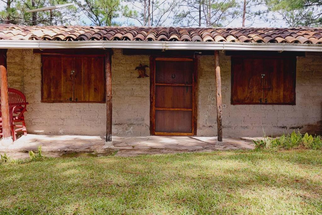 ein Haus mit zwei Holztüren und einem Rasenplatz in der Unterkunft Cabaña La tortuga in Siguatepeque