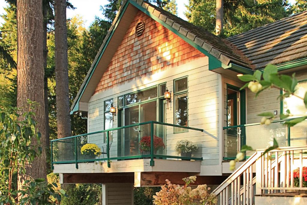 Casa blanca pequeña con balcón y árboles en The Quintessa Cottage, en Clinton
