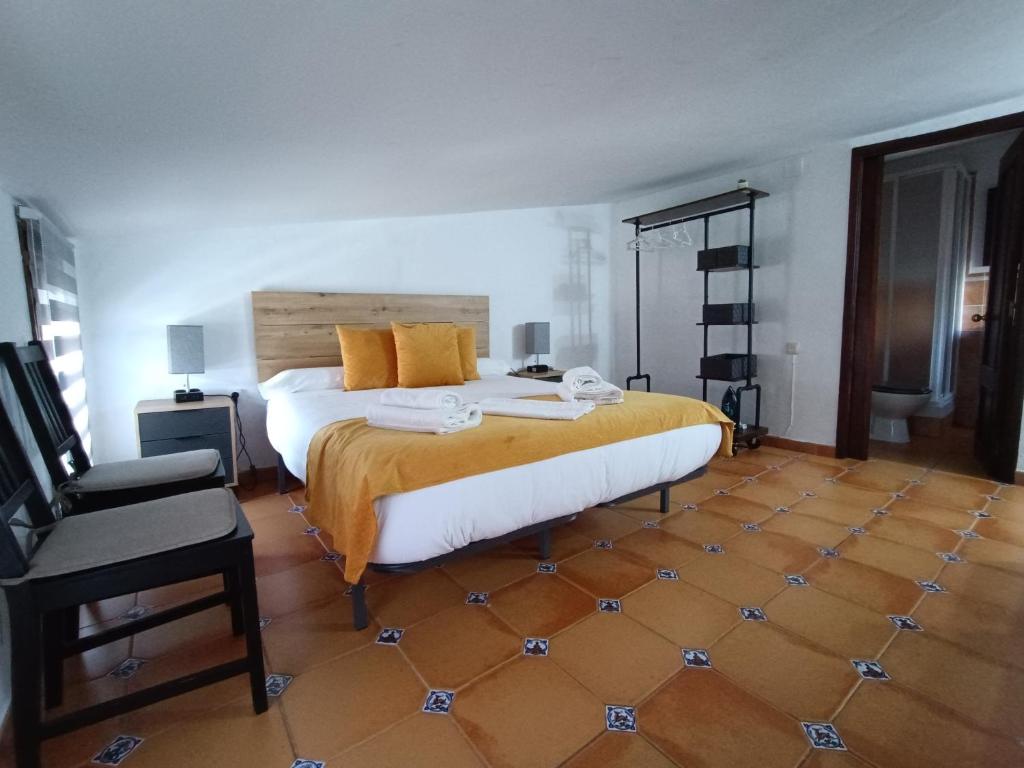 um quarto com uma cama grande e uma cadeira em La Casita em Úbeda