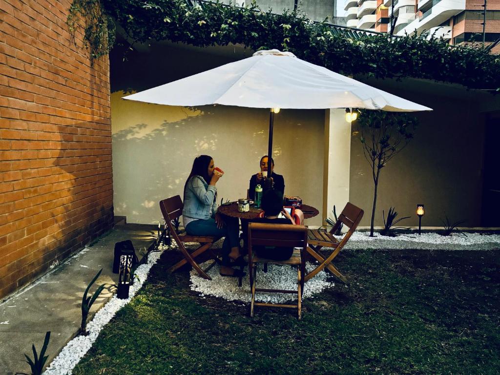 duas pessoas sentadas numa mesa debaixo de um guarda-chuva em NoMAD House em Guatemala