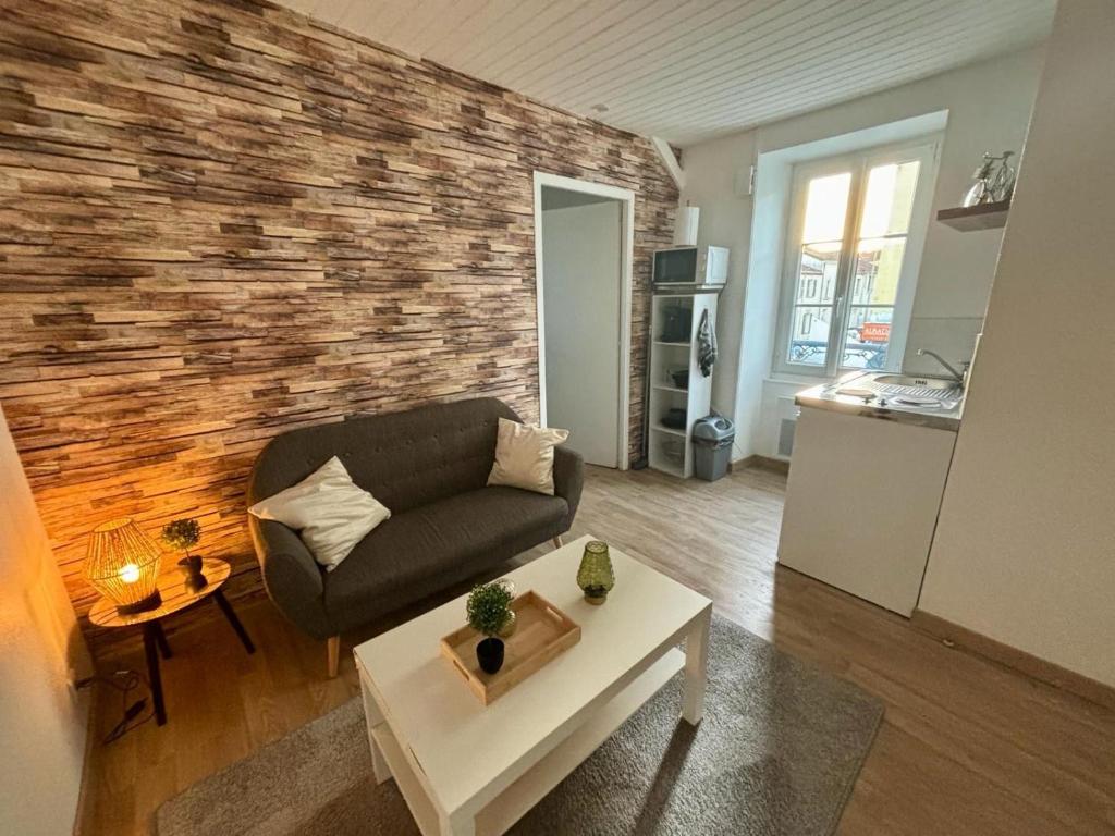 a living room with a couch and a brick wall at Appartement chaleureux in La Roche-sur-Yon