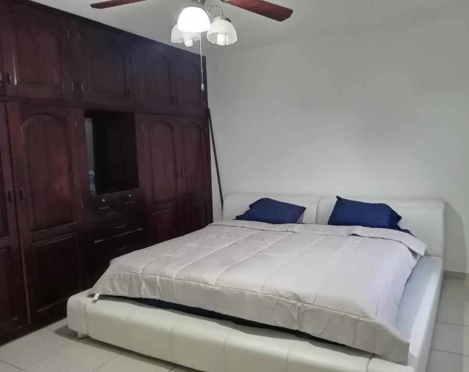 uma cama branca com almofadas azuis num quarto em A 5 MINUTOS DEL CORAZON DE TACNA em Tacna