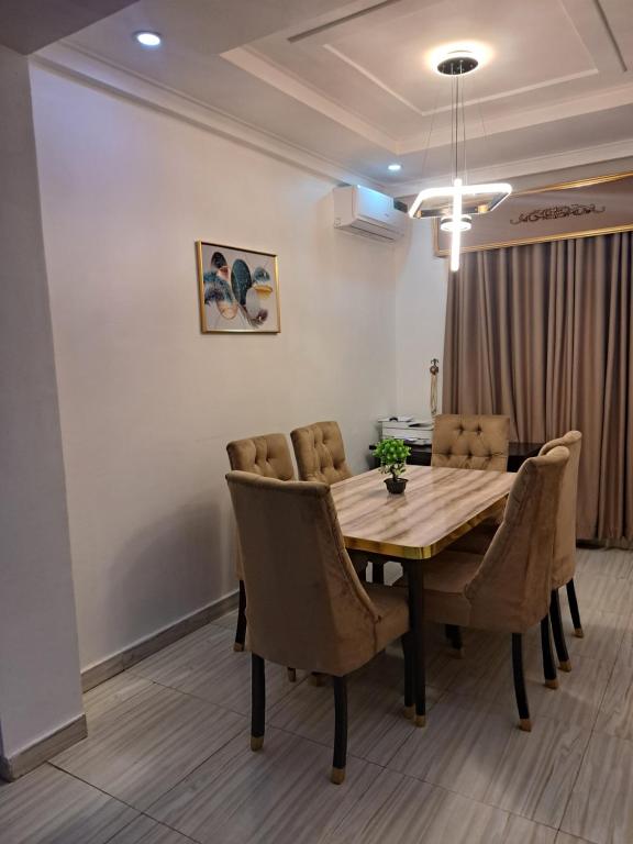 a dining room with a wooden table and chairs at GRACEPOINT APARTMENT in Rubuchi