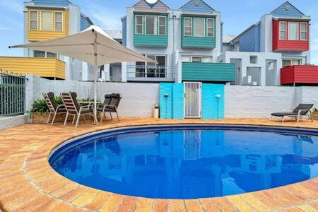 una gran piscina azul con sillas y sombrilla en 3-Bed with Alfresco Dining & Pool in Batemans Bay, en Batemans Bay