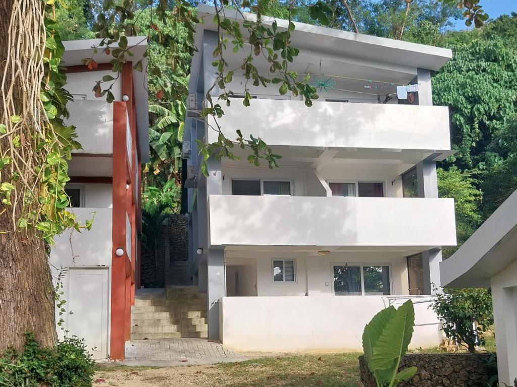 an external view of a white building with a red door at Olivers Binucot Beach House in Romblon