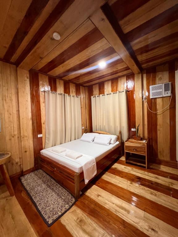 a bedroom with a bed in a wooden room at Ozar Homestay in Mambajao