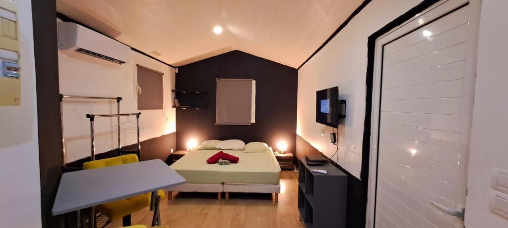 ル・ディアマンにあるLe Paradis des Petits Voyageurs - Maison d'Hôtes comprenant 1 Chambre et 1 Tente à 2km de la plage O'Mullane bas au Diamantのベッド、テーブル、椅子が備わる小さな客室です。