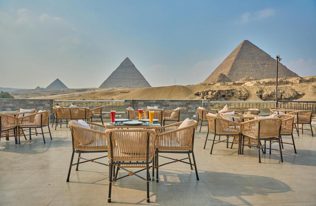 a restaurant with tables and chairs with pyramids in the background at Soul Pyramids View in Cairo