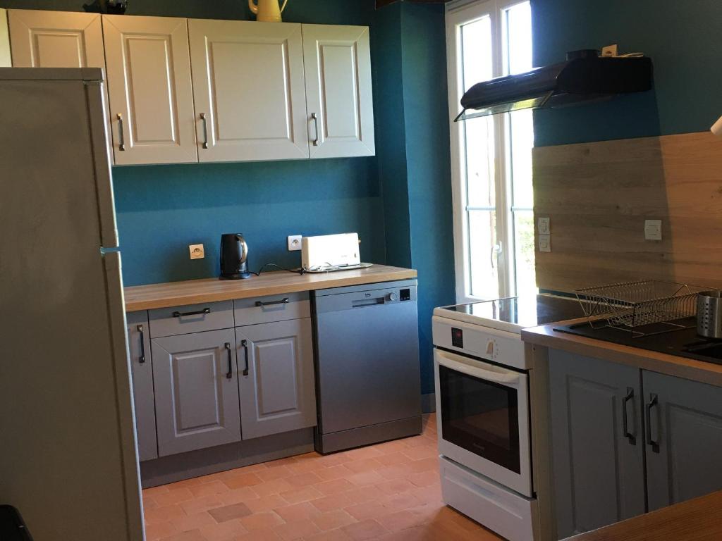 une cuisine avec des placards blancs et un mur bleu dans l'établissement Gîte Communauté de communes Brenne - Val de Creuse-Sauzelles, 4 pièces, 8 personnes - FR-1-591-118, à Sauzelles