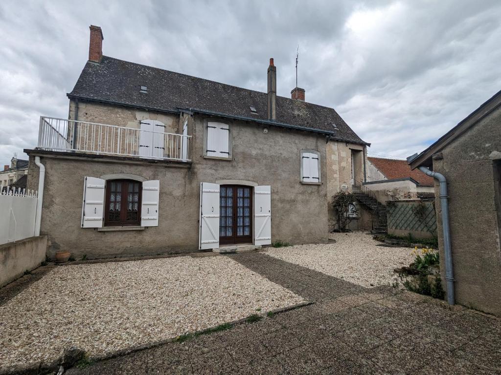 una vecchia casa di mattoni con finestre bianche e un balcone di Maison spacieuse avec cour et cheminée au cœur du Parc Naturel de la Brenne - FR-1-591-229 a Mézières-en-Brenne