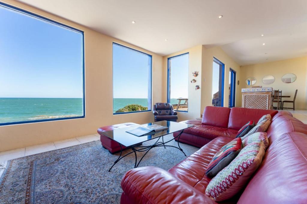 ein Wohnzimmer mit einem roten Sofa und großen Fenstern in der Unterkunft Casita Alegra Beachfront family friendly in Port Elliot