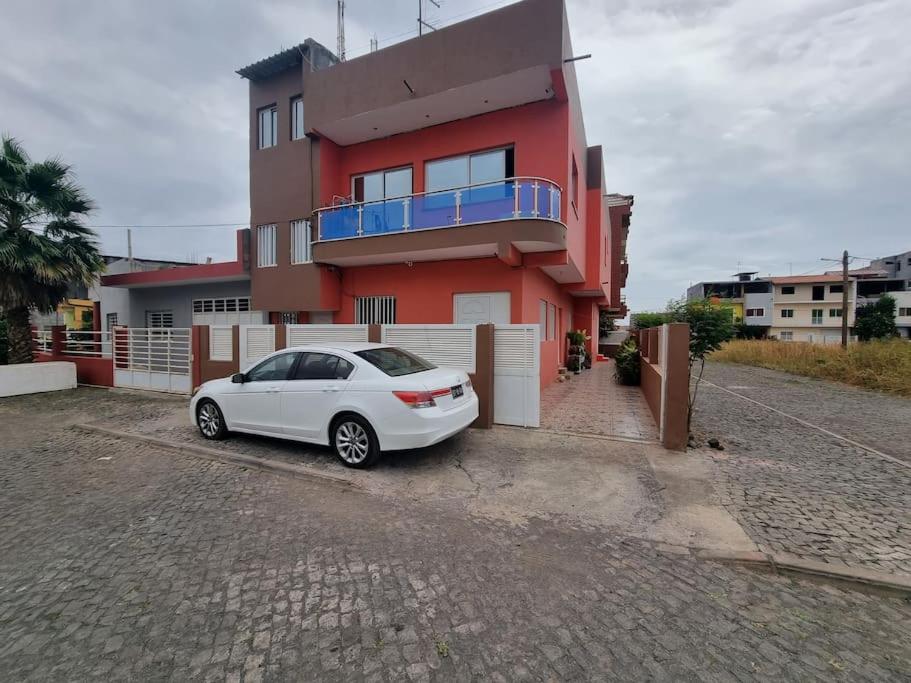 a white car parked in front of a red house at Apartment in Achada São Filipe in Praia
