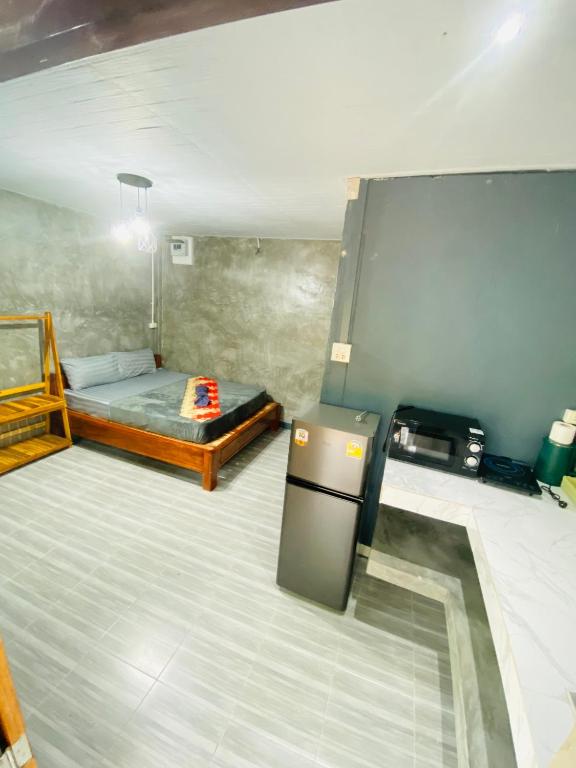 a room with a bed and a refrigerator in it at baan sugaiyah in Phra Ae beach