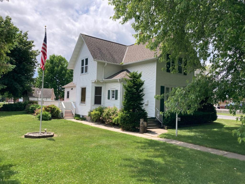 a white house with an american flag in the yard at Cozy Algoma Retreat! Minutes to Beach and Downtown! in Algoma