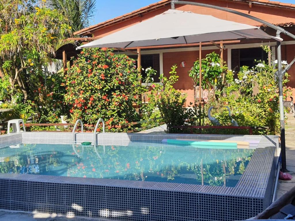 uma piscina com um guarda-sol em frente a uma casa em Casa em Ponto de Lucena em Lucena