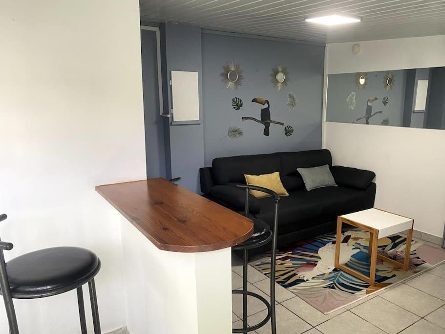 T2 calme à Remire-Montjoly في Rémire-Camp: غرفة معيشة مع أريكة سوداء وطاولة
