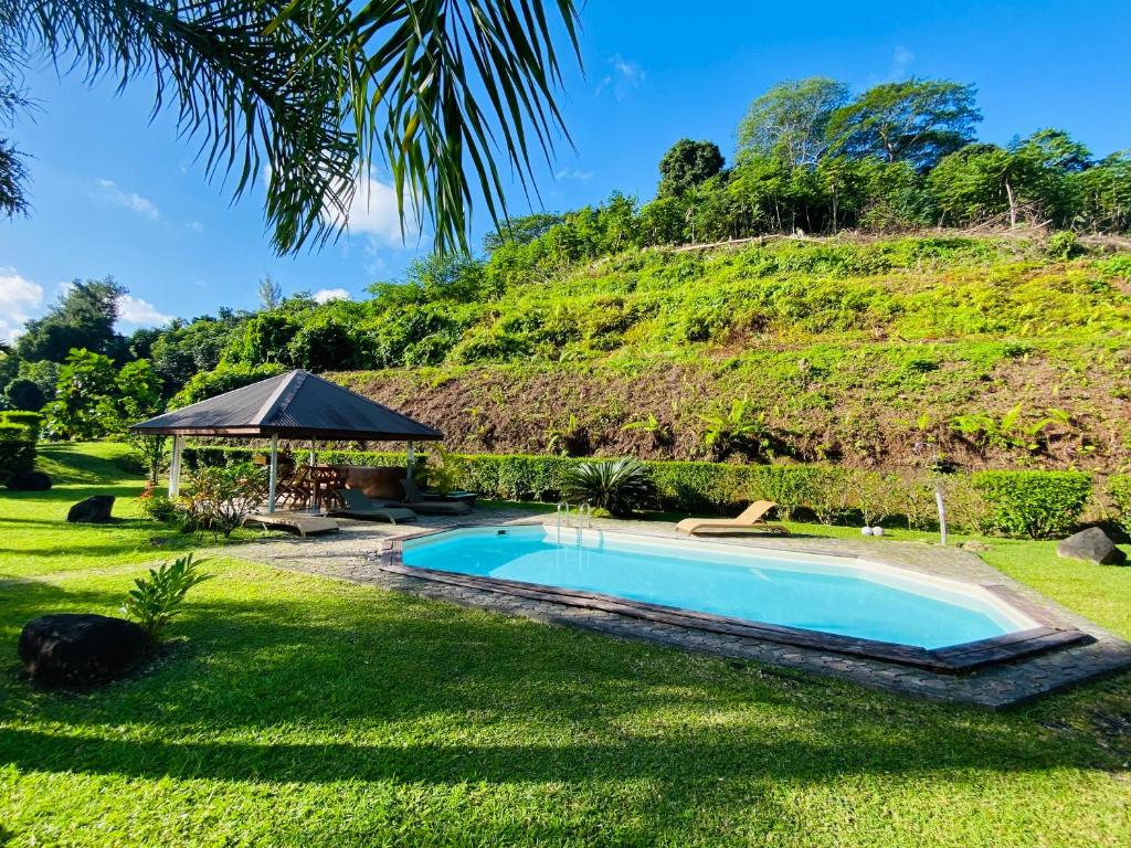 a swimming pool in a yard with a hill in the background at Bungalow Tiare in Uturoa
