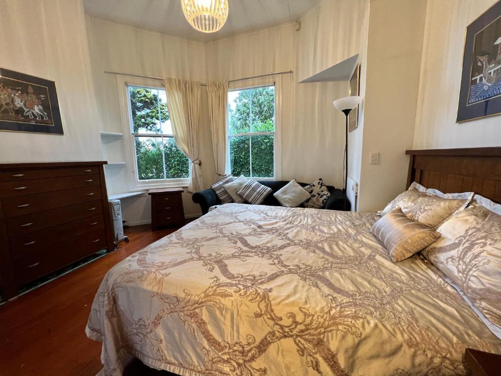 ein Schlafzimmer mit einem großen Bett und einem Sofa in der Unterkunft Grey Lynn House Auckland in Auckland