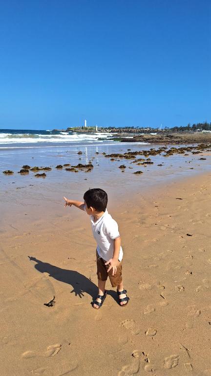 un joven parado en la playa en Surf Beach Bungalow, pet friendly and breakfast, en Surf Beach