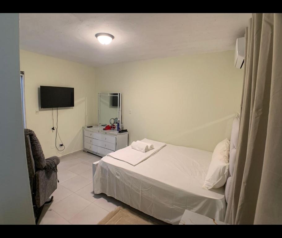 1 dormitorio con 1 cama blanca y TV en Sandy Airbnb, en La Caleta