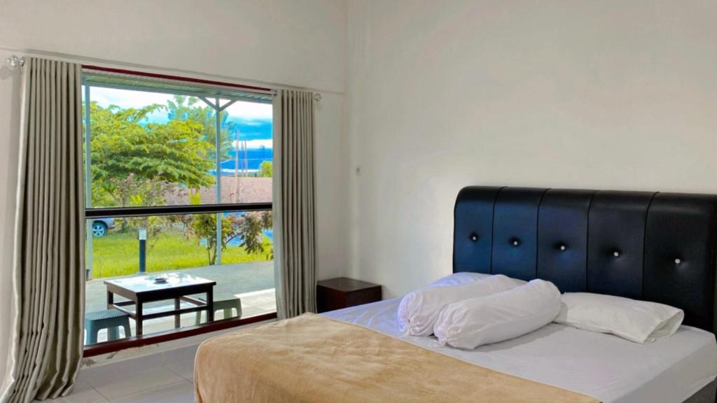 um quarto com uma cama e uma grande janela em Amadeo Guest House em Ratodena