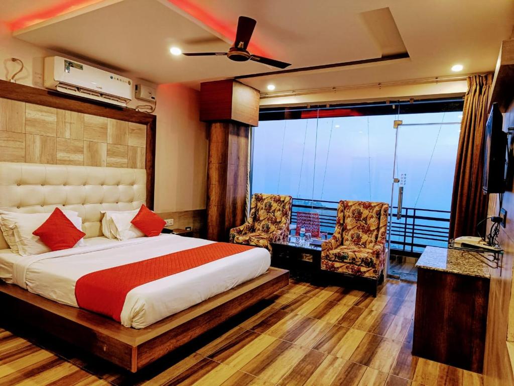 a bedroom with a bed and two chairs and a balcony at King Castle Mcleodganj in Dharamshala
