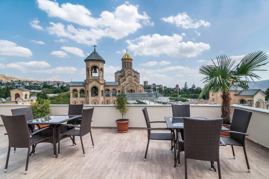 a balcony with tables and chairs and a building at Liva Hotel in Tbilisi City