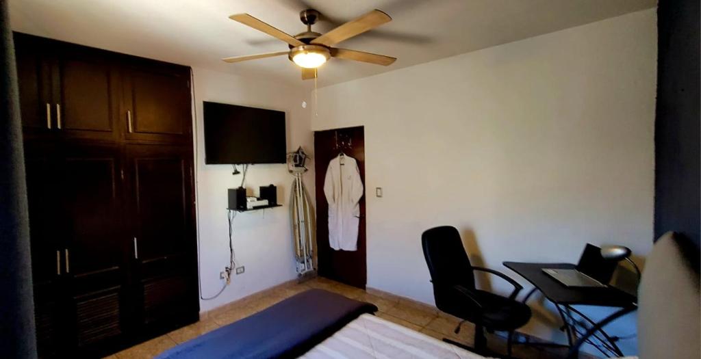 - une chambre avec un ventilateur de plafond, un lit et un bureau dans l'établissement Casa Arboleda, à Saltillo