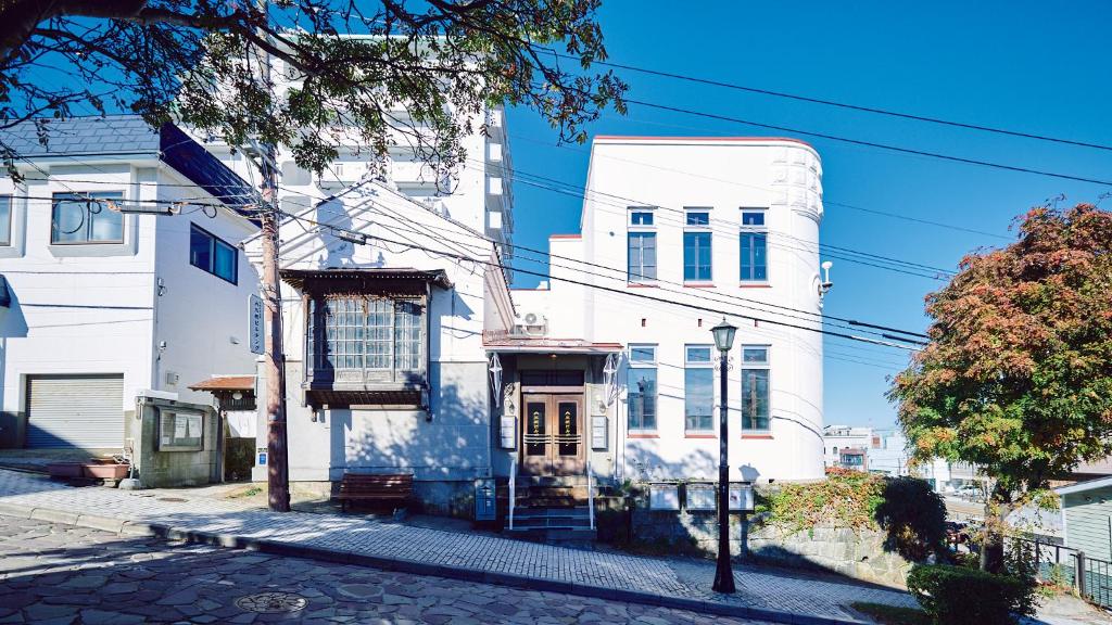 un edificio blanco con una puerta en una calle en SMALL TOWN HOTEL Hakodate, en Hakodate