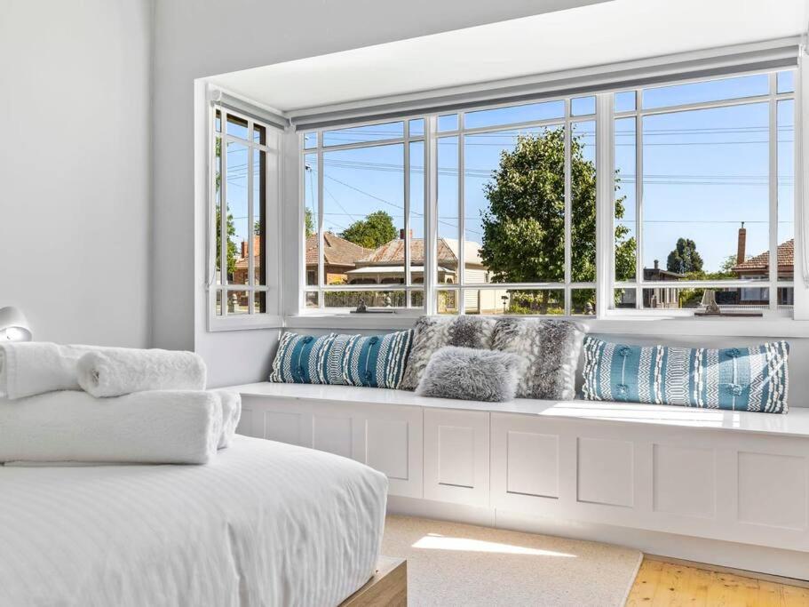 a white room with a window with pillows on a bench at NEW! Stunning 4BR Cottage In The Heart Of Ballarat - PET FRIENDLY & FAST WIFI in Ballarat
