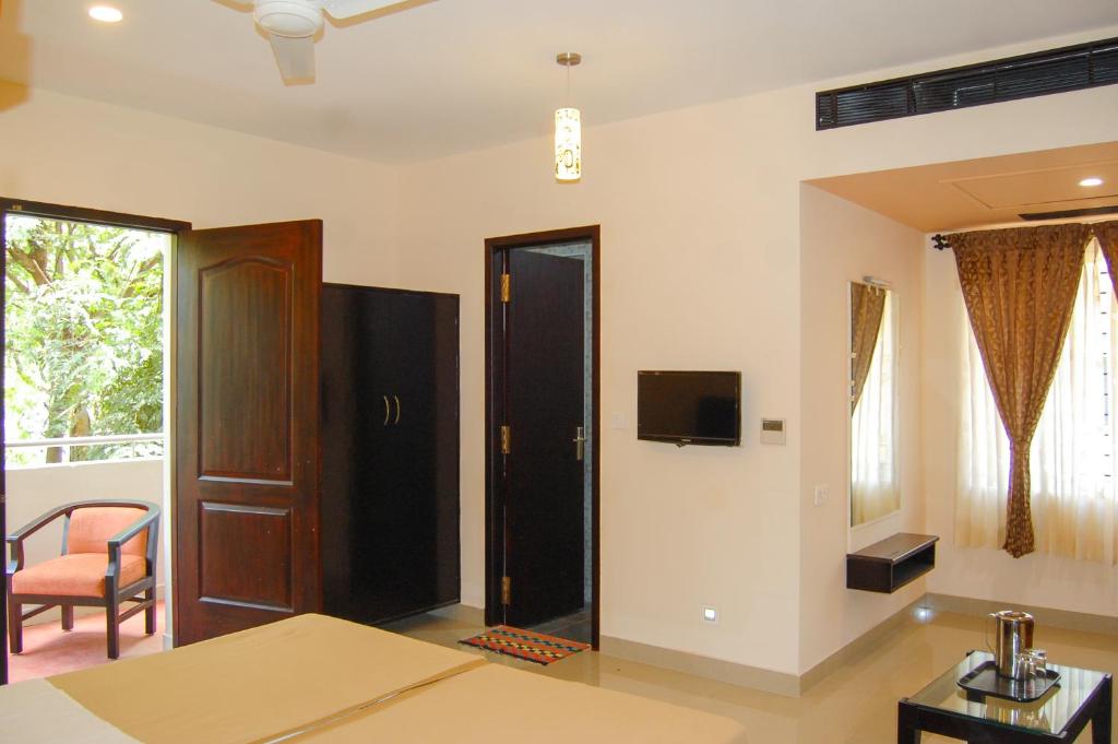 a room with a bed and a tv on the wall at Philomena Hotel & Apartment in Thanjāvūr