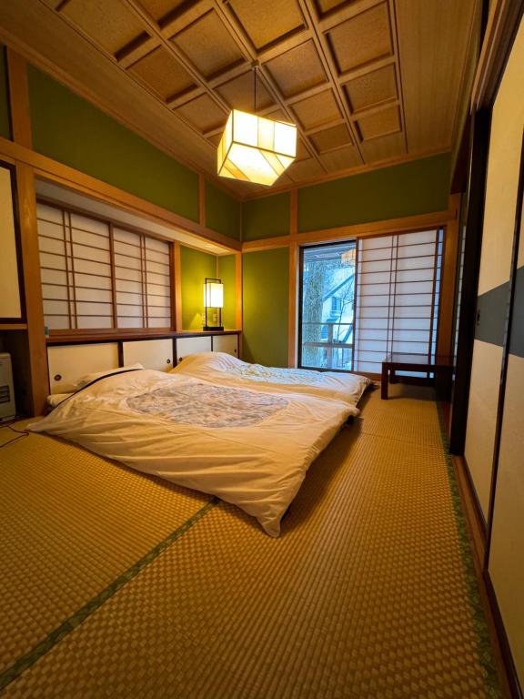 a large bed in a room with green walls and windows at 源泉掛け流し付き貸切別荘-Authentic private home with Private Kusatsu Onsen - THE HIDEOUT VILLA KUSATSU- in Kusatsu