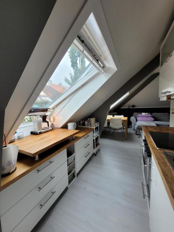 een zolderkeuken met witte kasten en een raam bij Cozy 2bdr apt. 3 min walk to Solsiden in Trondheim