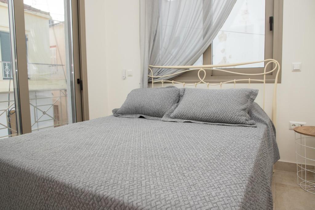 a bedroom with a bed with gray sheets and a window at Areti 1 & Areti 2 in Kilada
