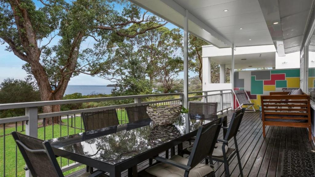 a balcony with a glass table and chairs on it at Beachfront- The Art Cottage- Pet Friendly in Vincentia