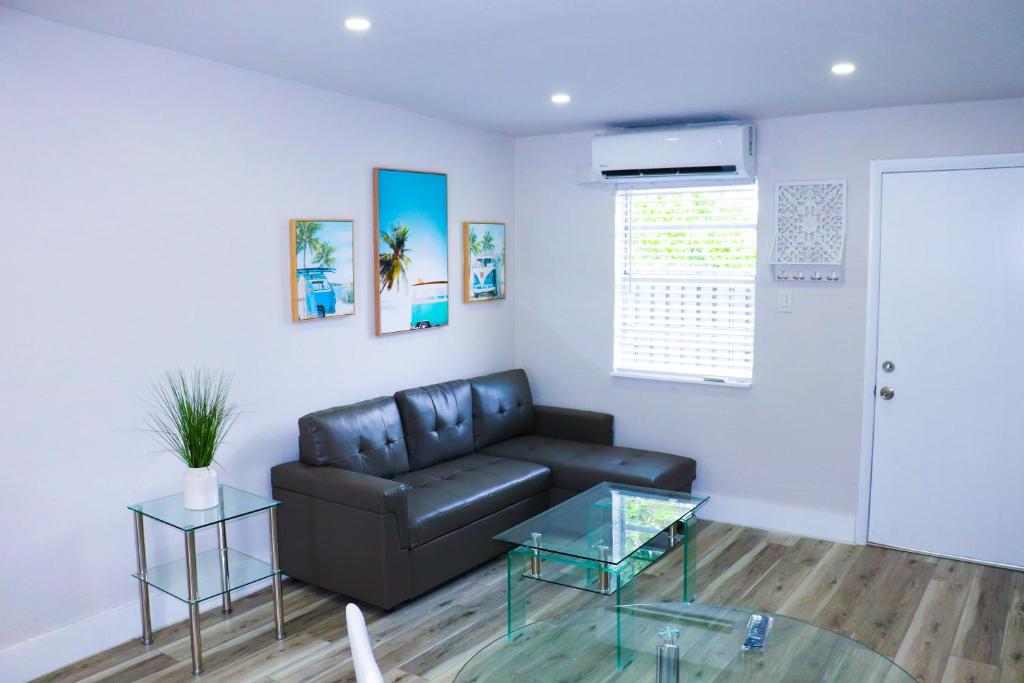 a living room with a leather couch and a glass table at Flamingo Beach House in Dania Beach