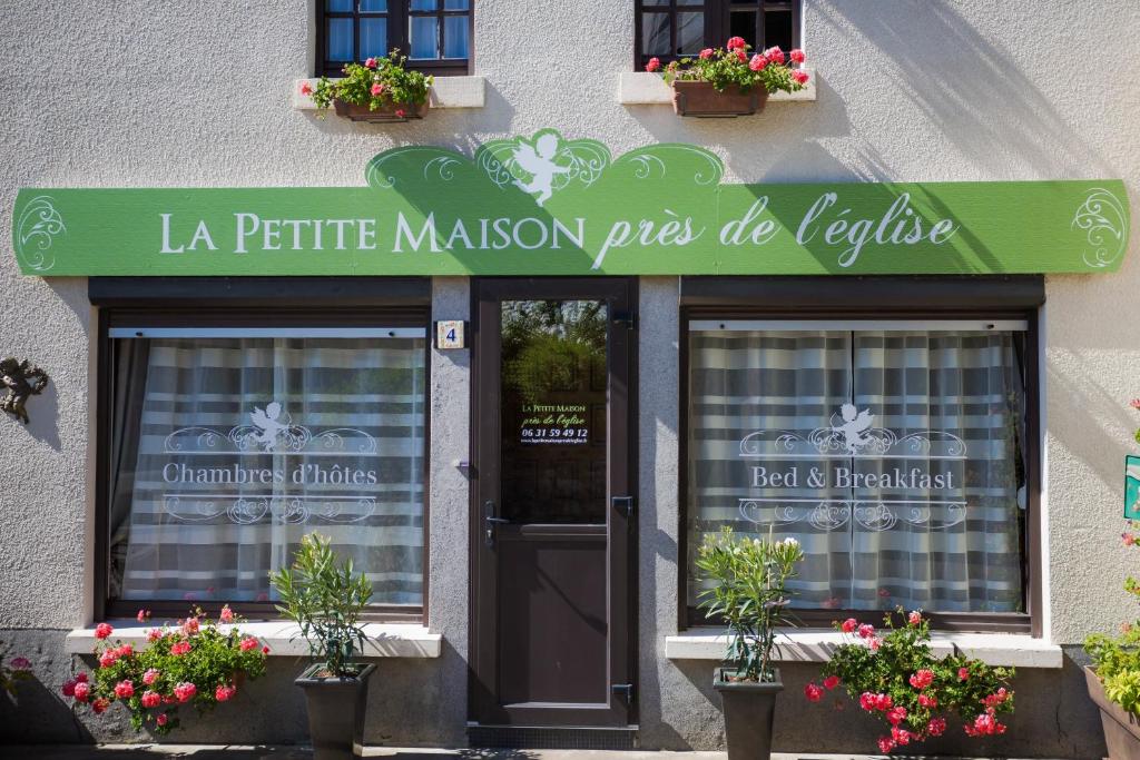 een gebouw met een groen bord boven een deur bij La Petite Maison près de l'Eglise in Meillac