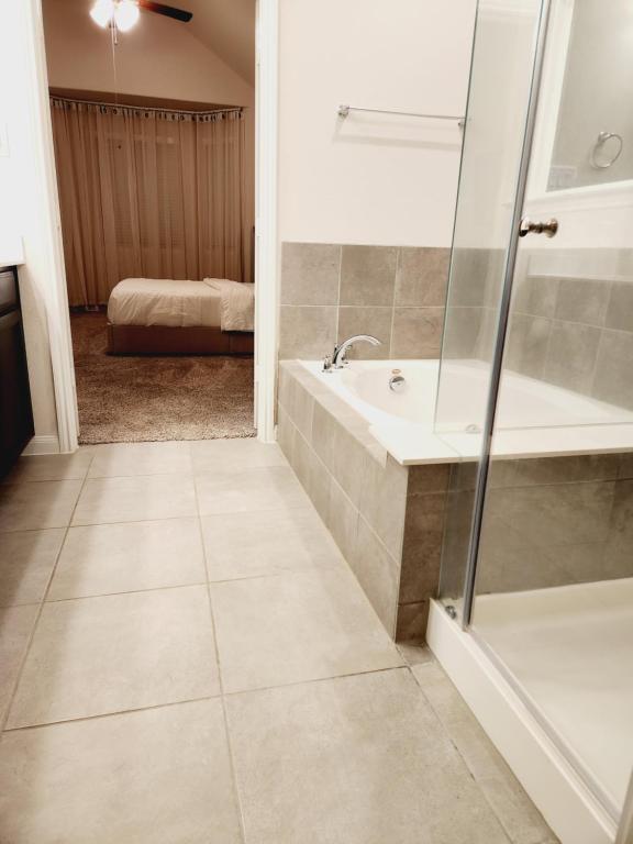 a bathroom with a shower and a tub and a sink at Shella Home in Missouri City