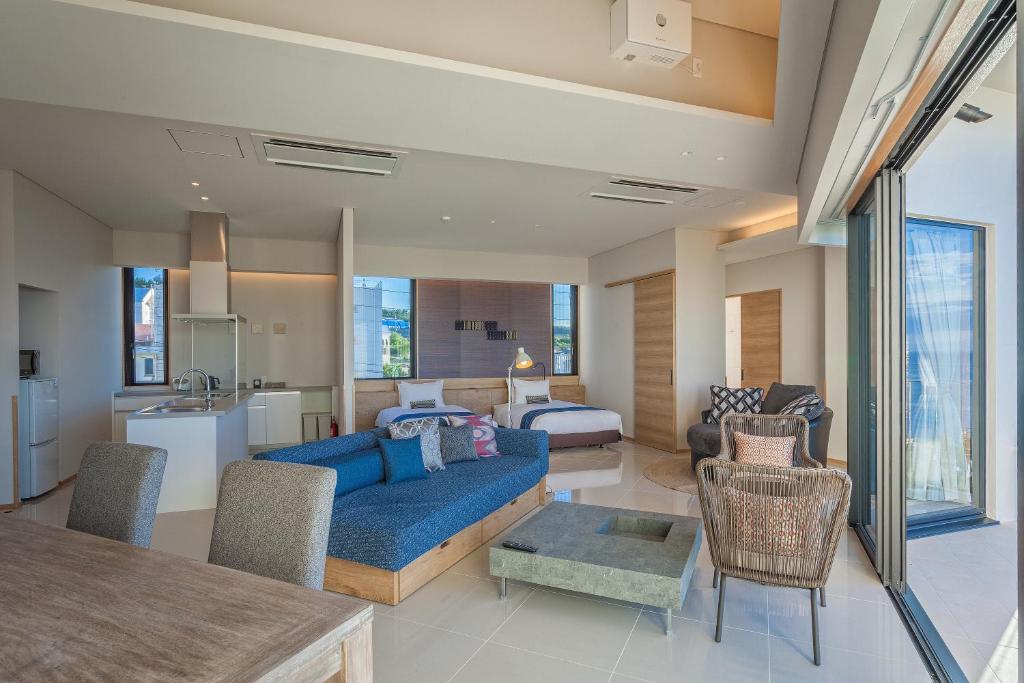 a living room with a blue couch and a bedroom at 恩納オーシャンビュースイート in Nakadomari