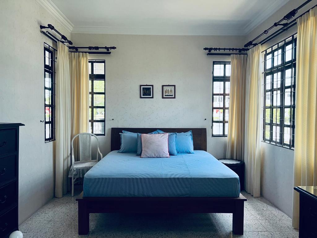 Schlafzimmer mit einem Bett mit blauer Bettwäsche und Fenstern in der Unterkunft Naura Homestay in Sungai Petani
