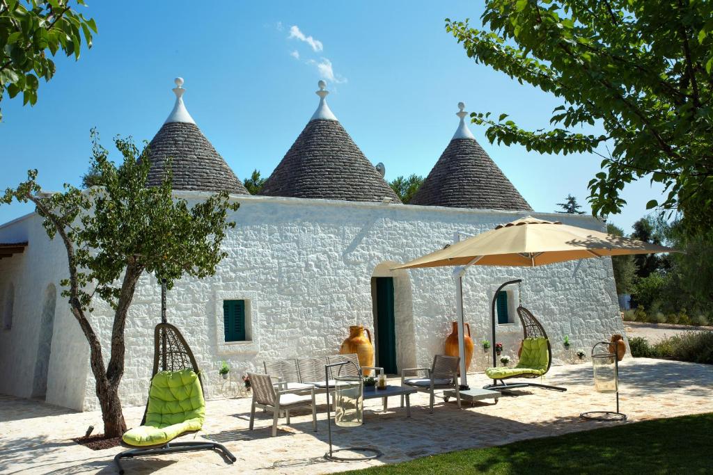 - un bâtiment avec une table, des chaises et un parasol dans l'établissement Trullo Divina (service fee waived), à Selva di Fasano